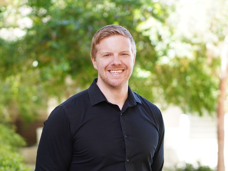 Daniel Relihan, PhD, smiling outdoors in a dark shirt